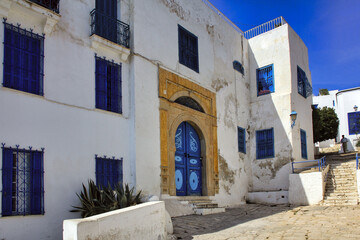 Fototapeta na wymiar Weißes Haus mit blauen Fenstern und gelber Tür in Tunesien