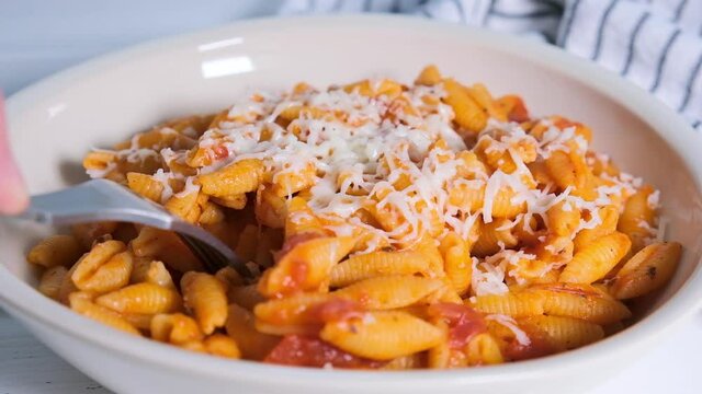 Gnocchetti sardi pasta in tomato sauce with cheese, gray background. Italian pasta concept.