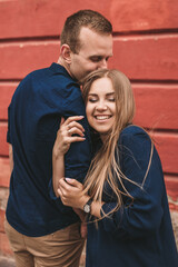 Happy young family on the background of a red wall. Young woman laid her head on her man's shoulder