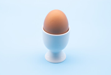 egg in a white cup isolated against a blue background