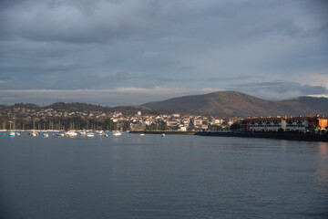 Fototapeta premium Barcos varados en el rió Bidasoa con Hendaya de fondo visto desde Hondarribia con un cielo nublado.