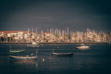 Barcos varados en el rió Bidasoa con Hendaya de fondo visto desde Hondarribia con un cielo nublado. - obrazy, fototapety, plakaty