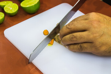 Latin Male Hand slicing fruit on white tray