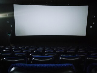 Fototapeta premium an empty cinema hall with blue seats. White screen for showing movies. Place for the label