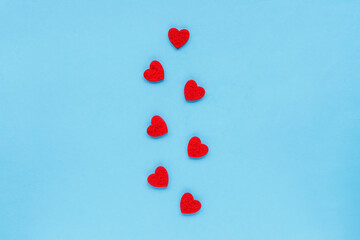 Ornament of red hearts on a blue background, top view, flat lay