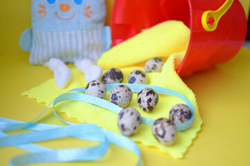 Festive Easter holiday greeting background. Easter decoration with quail eggs, ribbons on yellow and red background. Easter bunny in the background. Happy Easter concept. Copy space, selective focus.