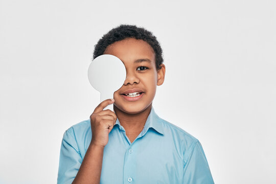 African American male kid having eye exam with one eye covering using an ophthalmic tool, on white background