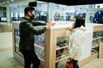 Obraz premium Asian couple wear face masks choose mobile phone at trade center.