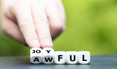 Hand turns dice and changes the word awful to joyful.