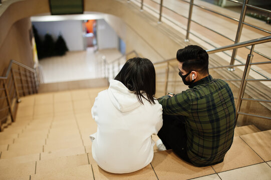Asian couple wear face mask sitting on stairs at trade center and kooking on smartphone.
