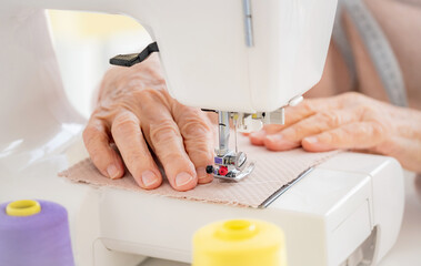 Close up view of old woman hands sewing on machine