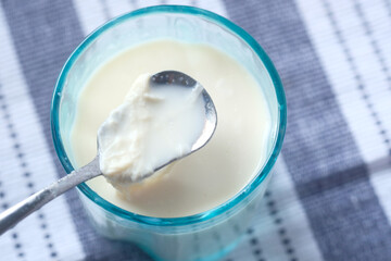 Close up of glass of milk and spoon on table 