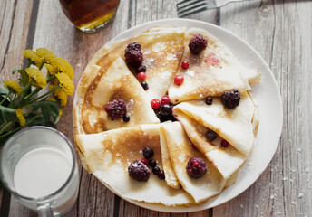 
Homemade pancakes, delicious thin pancakes with berries and maple syrup
