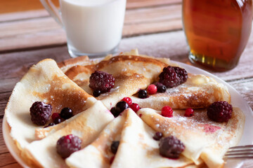 
Homemade pancakes, delicious thin pancakes with berries and maple syrup