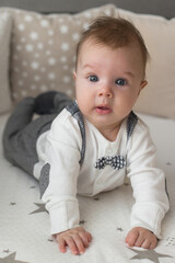 Fototapeta premium A cute little baby boy is surprised lying on the bed. Closeup portrait of newborn baby looking at camera