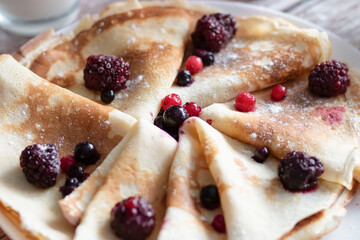 
Homemade pancakes, delicious thin pancakes with berries and maple syrup