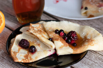 
Homemade pancakes, delicious thin pancakes with berries and maple syrup