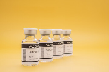 The covid-19 vaccine in glass bottles for prevention, immunization, and treatment from coronavirus infection on yellow background. Space for text. Concept of medical and vaccine