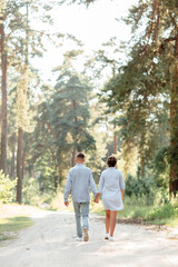 Fototapeta na wymiar young couple in love walking and enjoying the beautiful summer nature. woman and man, wearing in denim outfit are having date outdoors in the park. Romantic relationship. valentines day.