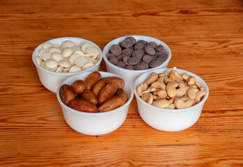 Food ingredients in white bowls. Cashews, dates, white and milk chocolate drops in white small bowls.