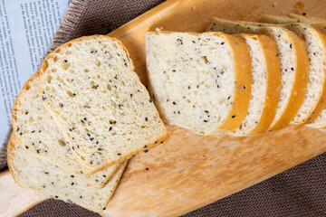 Black sesame bread freshly baked homemade is placed on a wooden cutting board and cut into equal strips. Good to eat for health.
