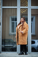 Glamorous african american woman in warm fur coat, eyeglasses pose at street.