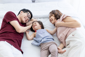 Girls with disabled disorders Learning of the brain Down syndrome constellations Laughing, merry, playing with her parents in the white bedroom bed. Happily Educational concept.