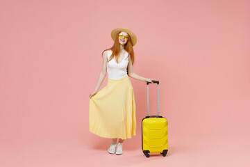 Full length traveler tourist woman wear summer clothes straw hat glasses with suitcase valise isolated on pastel pink background Passenger travel abroad on weekends getaway Air flight journey concept.