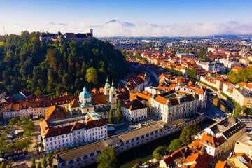 Fototapeta na wymiar Aerial view of Slovenian town of Ljubljana overlooking fortified castle on hill and Roman Catholic Cathedral in morning sunlight