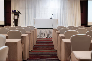 Business conferences or Seminar room with microphone on stage for presentation in luxury conference or meeting room and white chairs, Business and education in teaching classroom