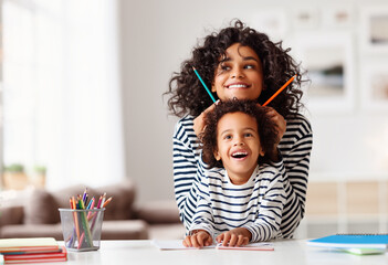 Ethnic mother and son laughing and grimacing and doing homework - obrazy, fototapety, plakaty