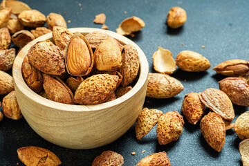 Almonds in brown wooden bowl on old wooden table background
