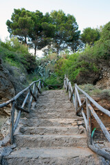 Stony steps with palisade that from the overlooking path lead to a cove along the coast. Salerno, Marina di Camerota, Italy.