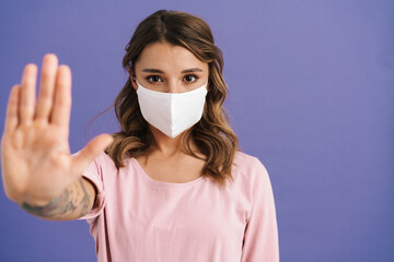 Caucasian girl in protective mask showing stop gesture