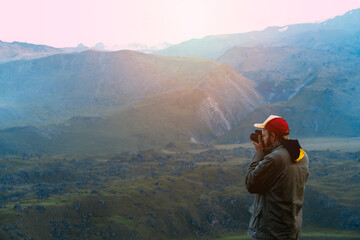 Fototapeta na wymiar A man in a jacket and a cap takes pictures of the mountains
