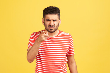Hey you! Angry bossy man with beard in striped t-shirt grimacing pointing finger at camera,...