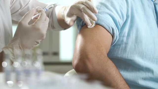 A nurse is injecting a vaccine to a patient in the clinic. Vaccination against coronavirus