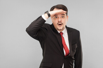 Handsome business man looking far away. indoor studio shot. isolated on gray background. handsome businessman with black suit, red tie and mustache looking at camera.
