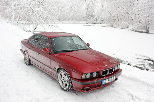 Chernigov, Ukraine - December 21, 2017: Red BMW car on the background of the winter park. Snowy winter and red car. Wonderful winter.	