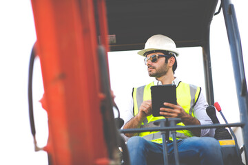 Construction Worker driving Excavator or Backhoe on construction building site. Young Hispanic Man...