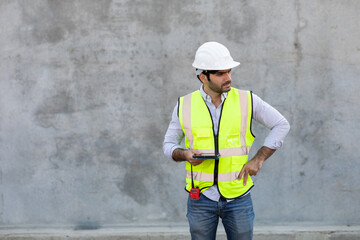 Construction Worker holding and looking on digital tablet isolate on gray cement background....