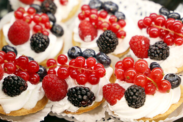 Creamy cakes with fresh berries, confectionery production. Sweet dessert with blackberries, raspberries and red currants