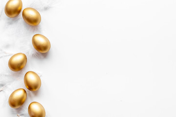Golden Easter eggs with white feather. Top view decoration