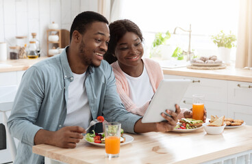 Obraz na płótnie Canvas Cheerful Black Couple Using Digital Tablet In Kitchen While Having Breakfast