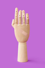Wooden hand with skin patch on color background