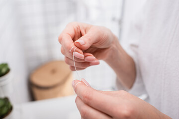 close up of woman holding dental floss in bathroom