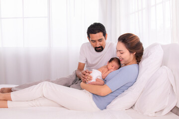 Beautiful women married man with beard Hispanic mix race, husband hold and looking wife and baby infant with love, mother embrace newborn son softly caring and protection on bed, happy family concept
