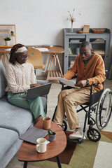 Vertical full length portrait of African-American couple with handicapped man working from home...
