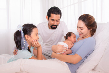 Beautiful woman married man with beard Hispanic mix race, happy family concept, daughter looking to newborn brother with love, father and mother embrace newborn son softly caring, protection on bed