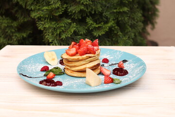 Pancakes with strawberries and chocolate in a cafe, delicious sweet breakfast